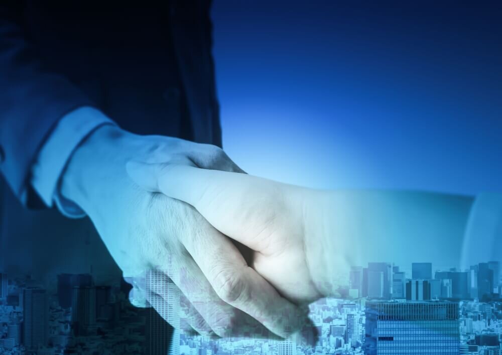 ビジネスマンの握手と青い都市風景